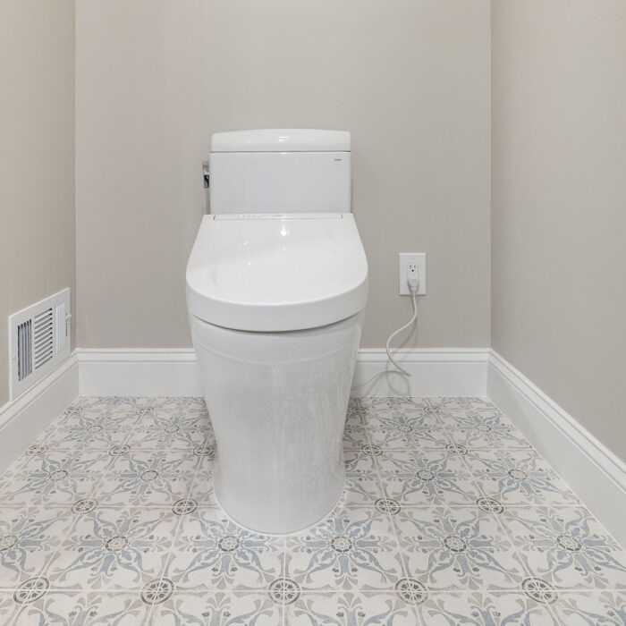 Modern white toilet on patterned tile floor