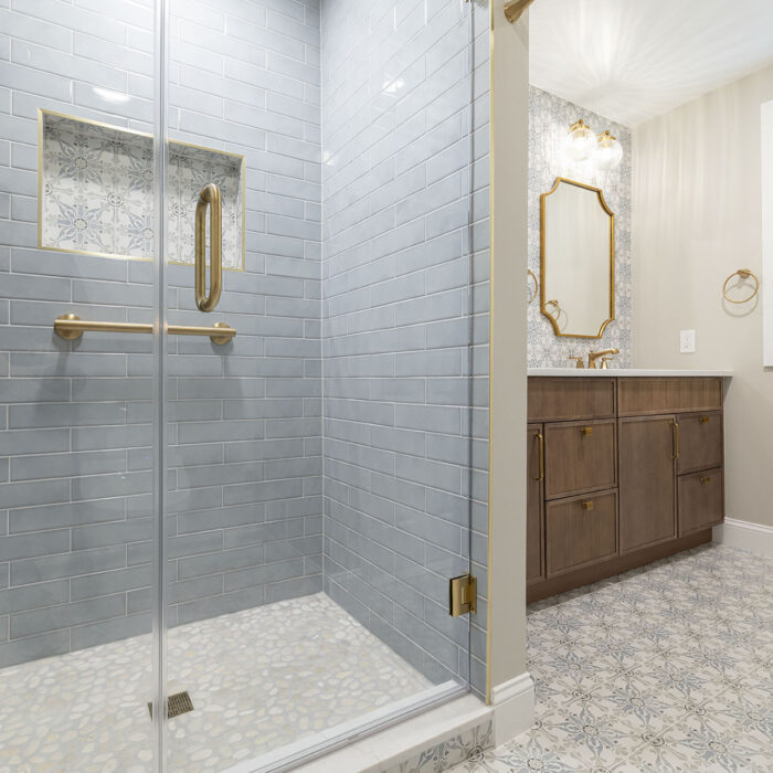 Glass shower with gray tile and gold fixtures