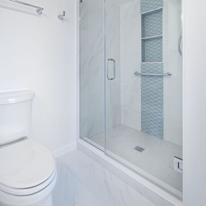 White bathroom with glass shower and mosaic tile
