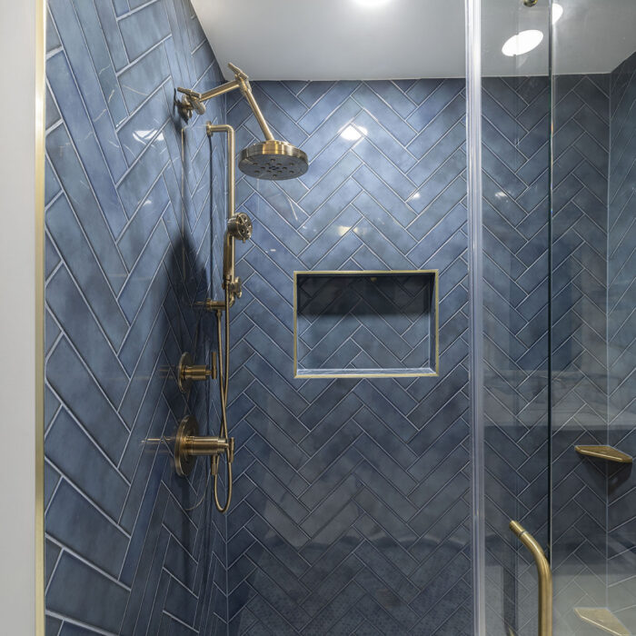 Blue herringbone tiled shower with brass fixtures