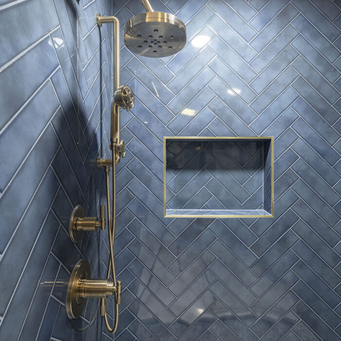 Blue herringbone tile shower with brass fixtures