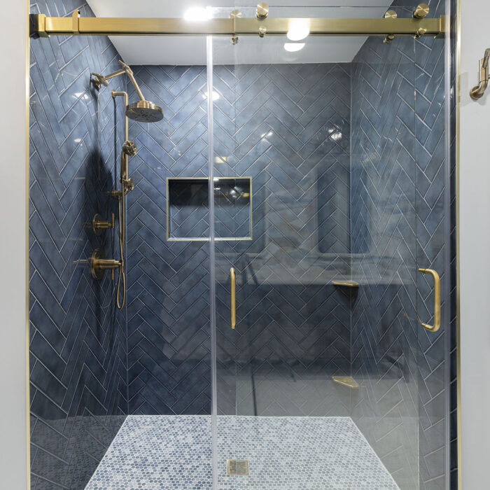 Navy herringbone tile shower with brass fixtures