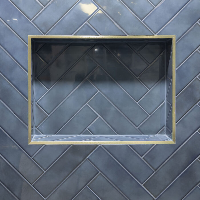 Brass-trimmed recessed niche on blue herringbone tiles