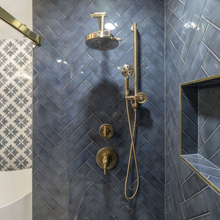 Blue herringbone tile shower with brass fixtures