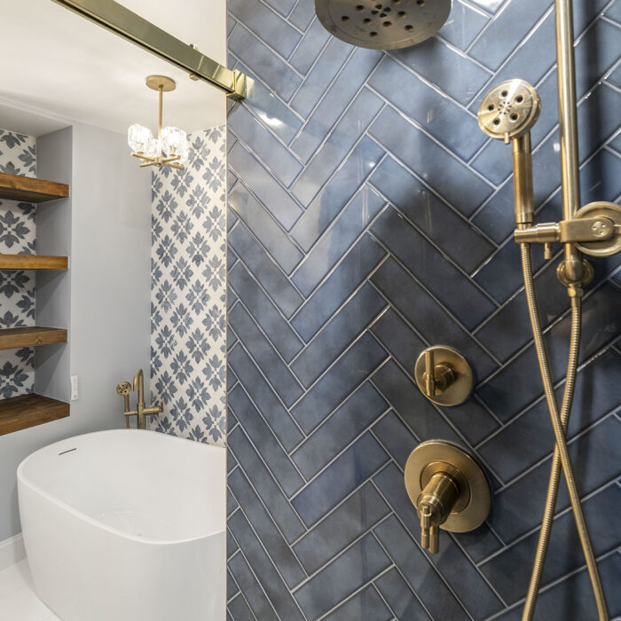 Brass shower fixtures on blue herringbone tile