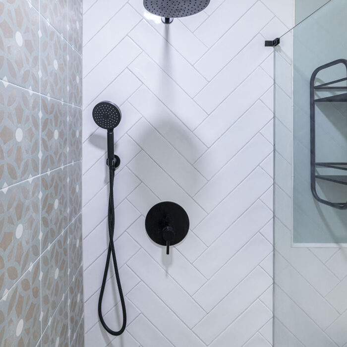 Black rain showerhead on white herringbone tiles