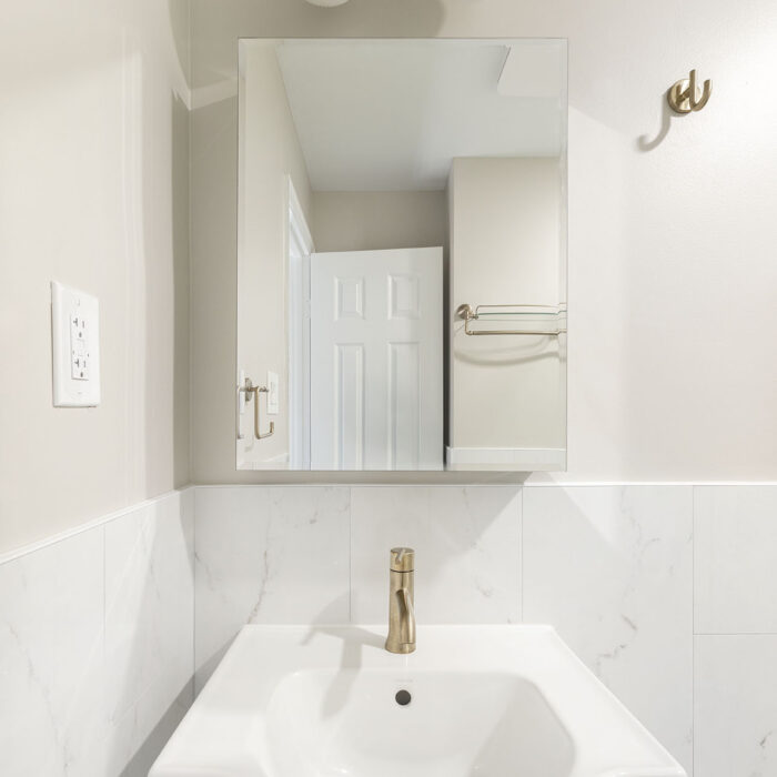 White pedestal sink with mirror and brass light