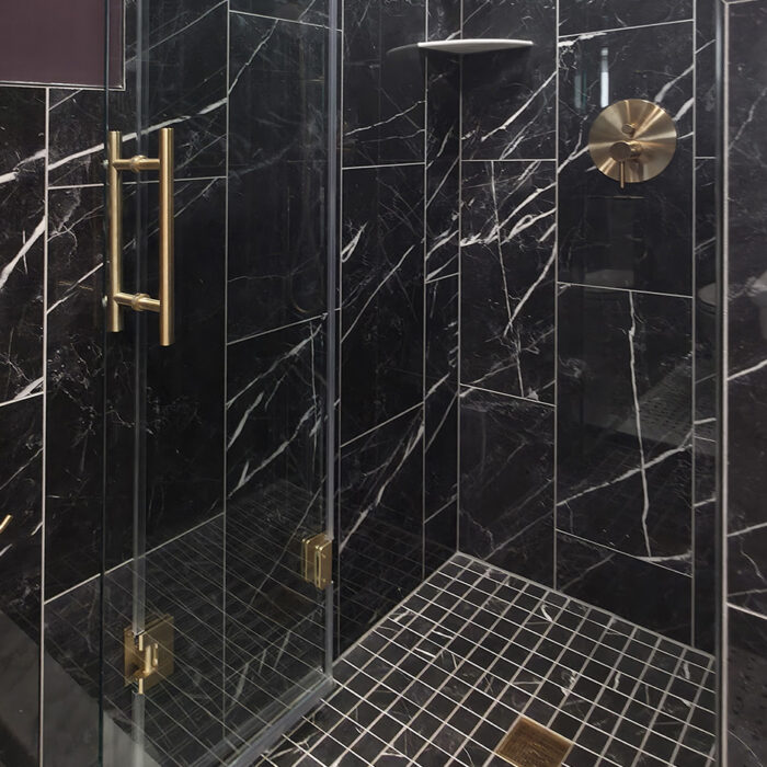 Glass shower with black marble and brass fixtures