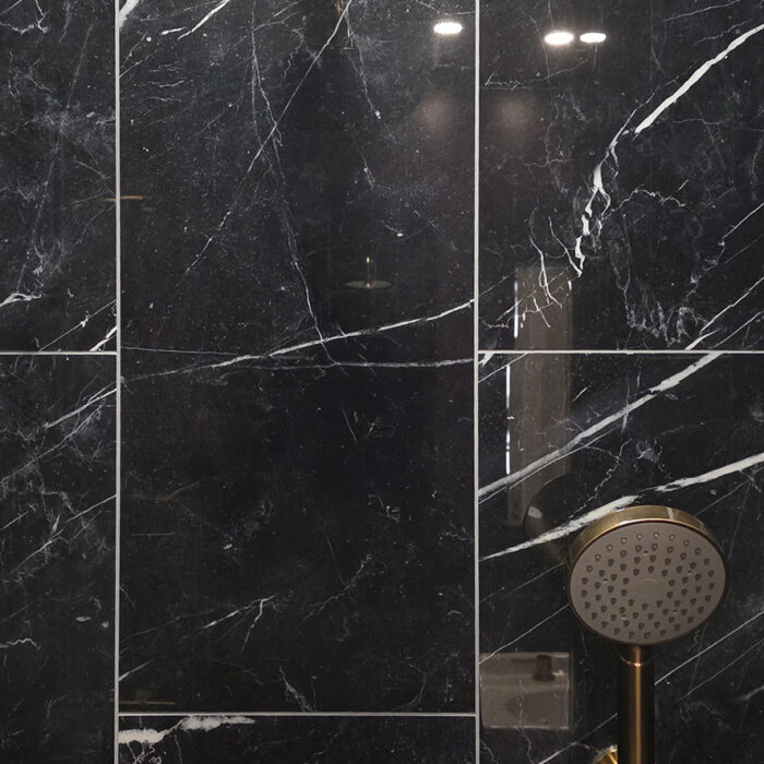 Black marble shower with brass rainfall and handheld