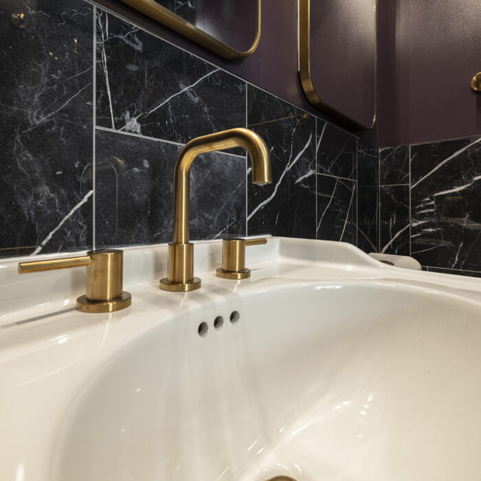 Brass faucet, white sink, black marble backsplash